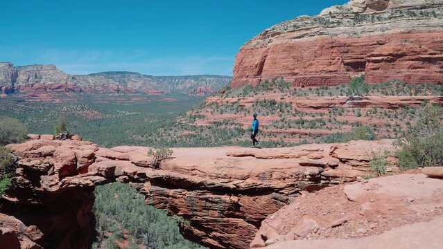Sedona is known for its red sandstone formations and energy vortexes. Tourist walking on Devil's Bridge hike
