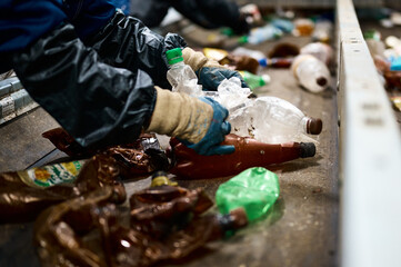 Worker sorts trash on conveyor belt at waste recycling plant