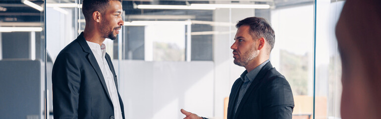 Two business colleagues talking together while standing in meeting room