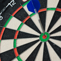 Single Bullseyes in Steel Tip Dartboard, blue flight stuck in red bullseye of bristol board. - obrazy, fototapety, plakaty