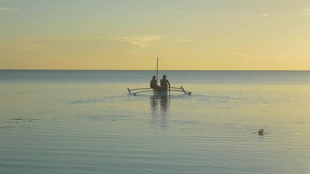 Fishermen go fishing at sunset in a traditional boat, in the Philippines