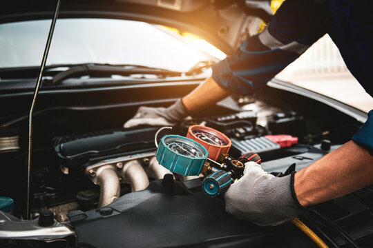 Car care maintenance and service, Hand technician auto mechanic using measuring manifold gauge check refrigerant and filling car air conditioner to fix repairing heat conditioning system.