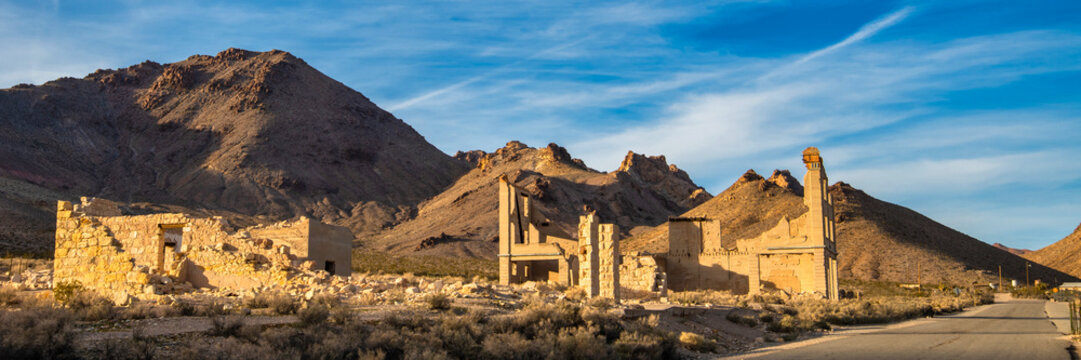 Ghost town stone ruins of an old building in a mountainous desert landscape on a clear day.
