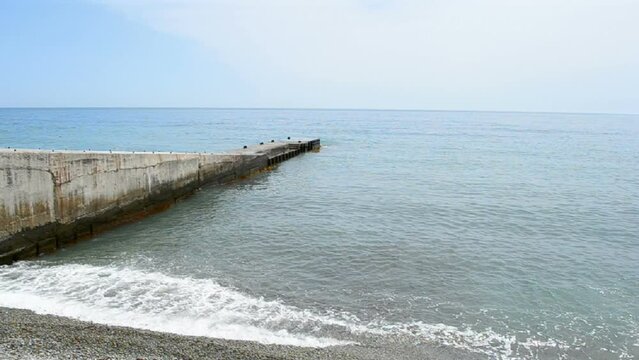 stone barrier protection against waves (long concrete  barricade wall construction), blue ocean, blue sky in sunny day, summer environment diversity