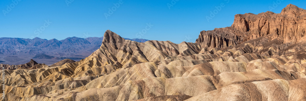 Wall mural panoramic view of remote desert mountains and rolling hills with colorful layers of rock on a clear 