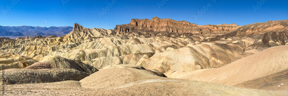Wall mural panoramic view of remote desert mountains and rolling hills with colorful layers of rock on a clear 
