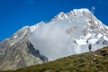 Hiker enjoying the view while hiking the Tour Du Mont Blanc from italian side
