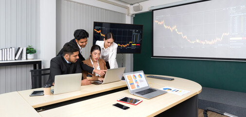 Group of business people in suit analyze stock information in the meeting room. Business executives team meeting in modern office with laptop computer, tablet, mobile phone on table.