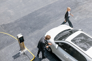 Aerial view progressive lifestyle of businesspeople with electric car connected to charging station...