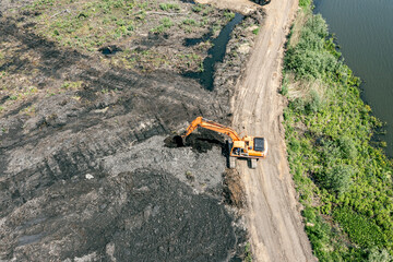 big industrial excavator working in swamp countryside at sunny day. aerial view from flying drone.