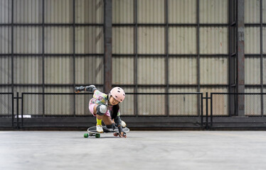 asian child skater or kid girl fun playing skateboard or ride surf skate with crouching turn or sitting snap in street skate park and extreme sports to wear helmet elbow wrist knee guards body safety © kornnphoto