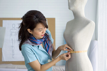 Fashion designer room. Young asian dressmaker in striped scarf use tape measure, measuring waist...