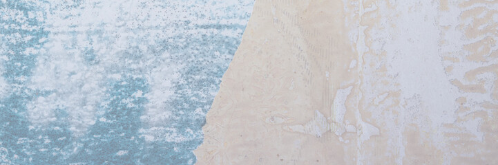 Torn old faded paper wallpaper with a retro pattern. Tattered scraps of paper on the wall. Wide panoramic texture for background and design.