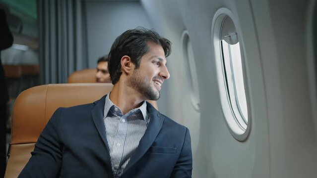 Indian businessman open the window of the plane to see the view outside from seat. Smile and enjoy the journey