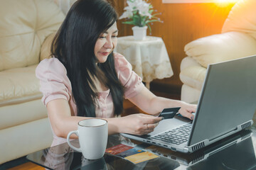 Asian young woman's resting and using credit card for online shopping and browsing internet with laptop. Entrepreneur or Businesswoman working from home. Online concept.