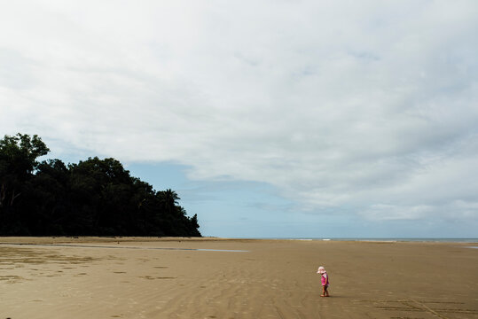 High angle view of girl standing at beach against cloudy sky