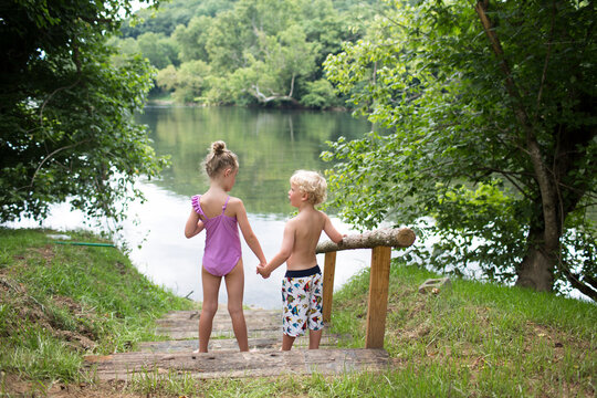 High angle view of siblings holding hands while standing on steps against lake