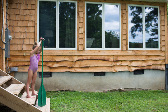 Girl wearing one piece swimsuit while holding oar on steps
