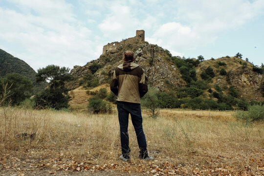 Full length of man looking at view while standing on field against mountains
