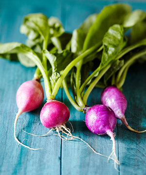 Close-up of radishes with leaves on wooden table