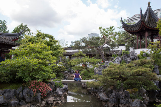 Man meditating on footbridge over lake amidst Chinese Garden at Sun Yat-Sen