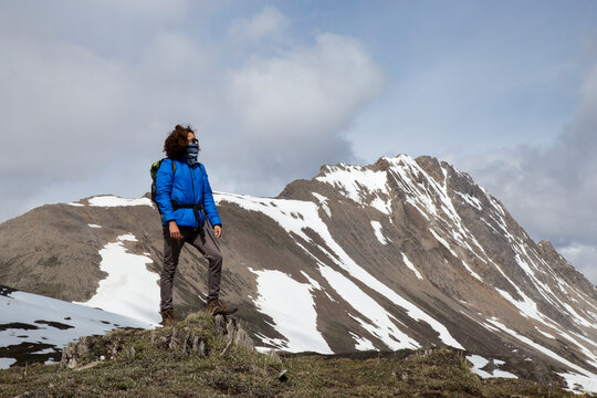 Full length of hiker with scarf covering mouth looking at view against mountains