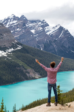 High angle view of hiker with arms raised standing against Peyto Lake and mountains