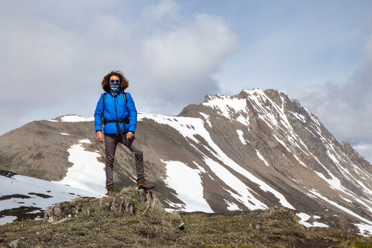 Full length of confident hiker with scarf covering mouth against mountains