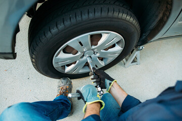 High angle view of man tightening tire with spanner at driveway