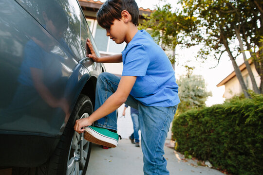 Boy tightening tire with spanner at driveway