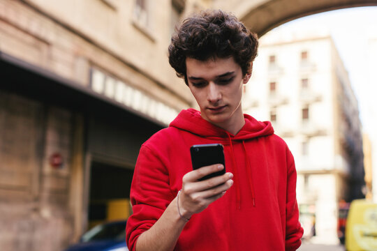 Teenage boy using smart phone in city