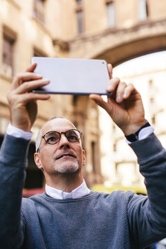 Man photographing with tablet computer in city