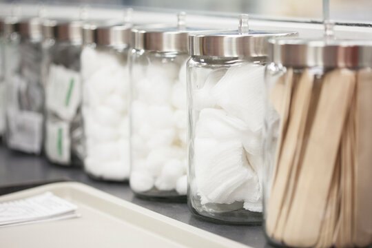 Close-up of cotton balls, medicines and tongue depressors in canisters at medical clinic