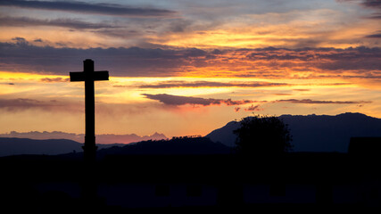 Silhouette cross against cloudy sky during sunset