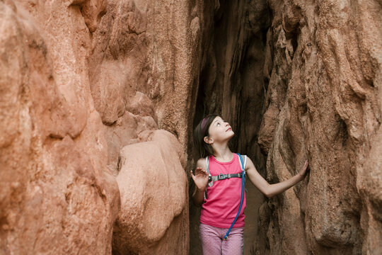 Girl looking up while standing amidst rock formations