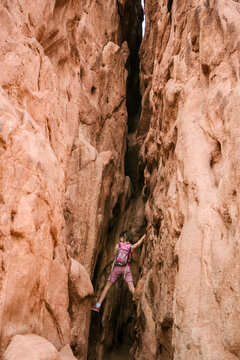 Low angle view of girl with backpack climbing rock formations