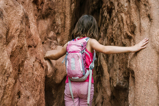 Rear view of girl with backpack exploring amidst rock formations