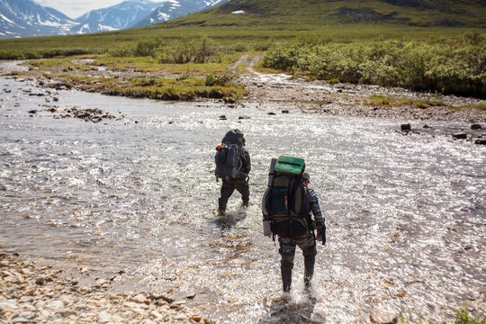 Rear view of hikers walking in river