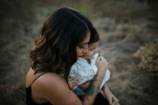 High angle view of mother holding son while sitting on field