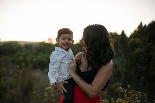 Portrait of smiling son carried by mother on field