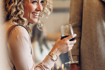 Cheerful businesswoman holding wineglass while looking away in hotel