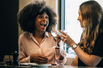 Cheerful businesswomen toasting drinks in hotel