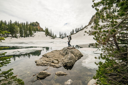 Side view of man standing on rock in lake against sky