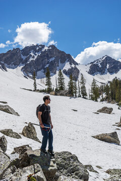 Full length of man standing on rocks at snowcapped mountain against sky
