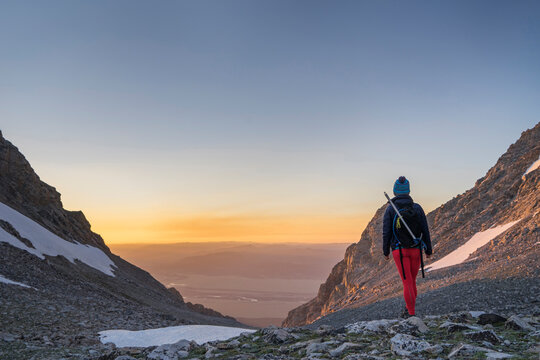 Rear view of female hiker standing on mountain against sky during sunset