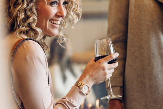 Cheerful businesswoman holding wineglass while looking away in hotel