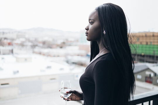 Side view of thoughtful businesswoman holding drink while looking away in hotel balcony