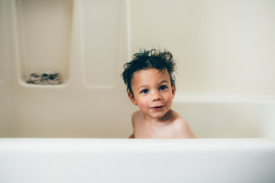 Portrait of shirtless wet boy sitting in bathtub at home