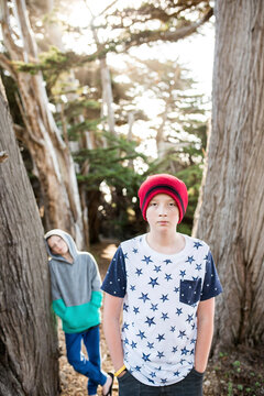 Portrait of confident boy with hands in pockets while friend standing by tree at park