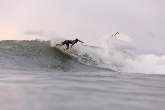 Shirtless man surfing on sea against cloudy sky